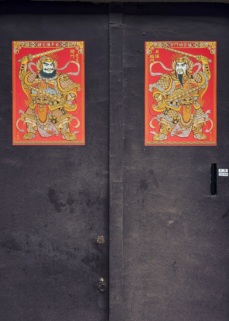 Puertas oscuras con dos carteles rojos de figuras ornamentadas.