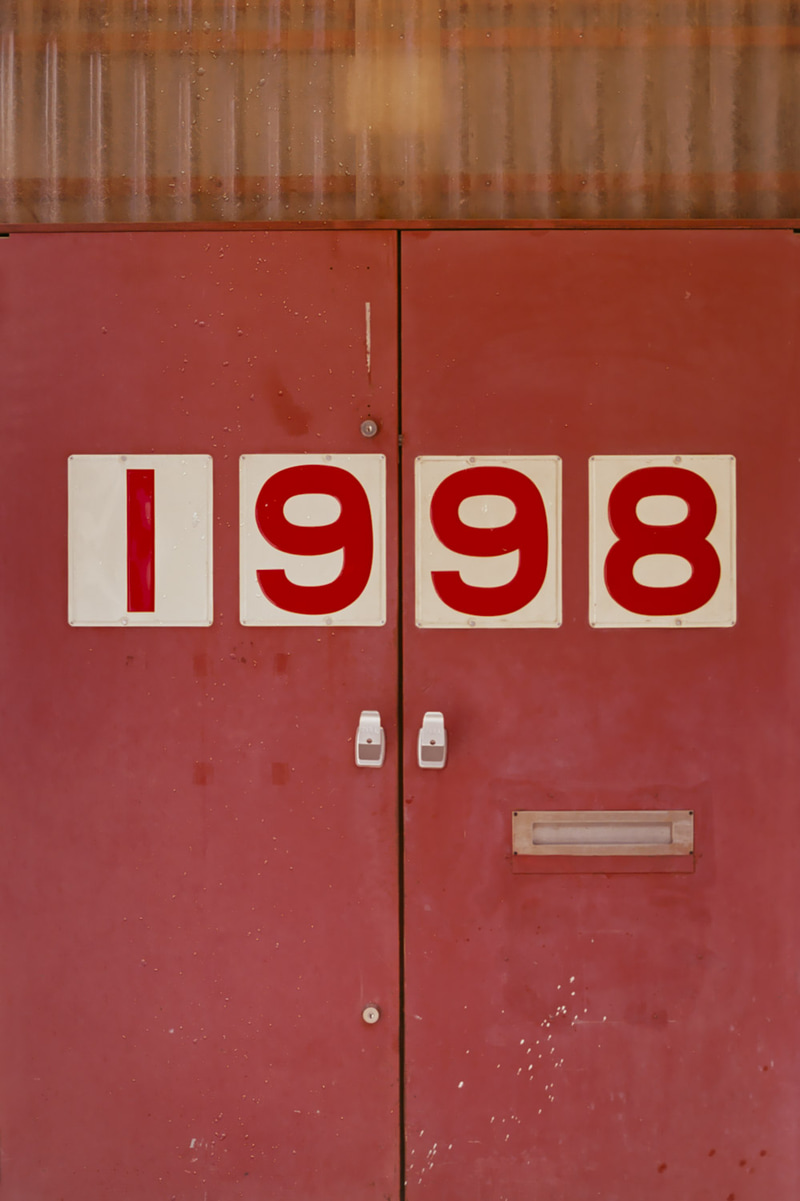 Puertas dobles rojas con grandes cifras blancas que forman 1998.