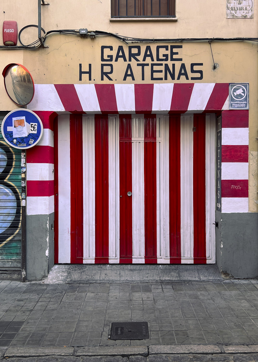 Puerta de garaje con franjas verticales rojas y blancas bajo un letrero.