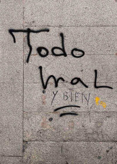 Grafiti «Todo mal» y un rostro triste sobre una pared gris